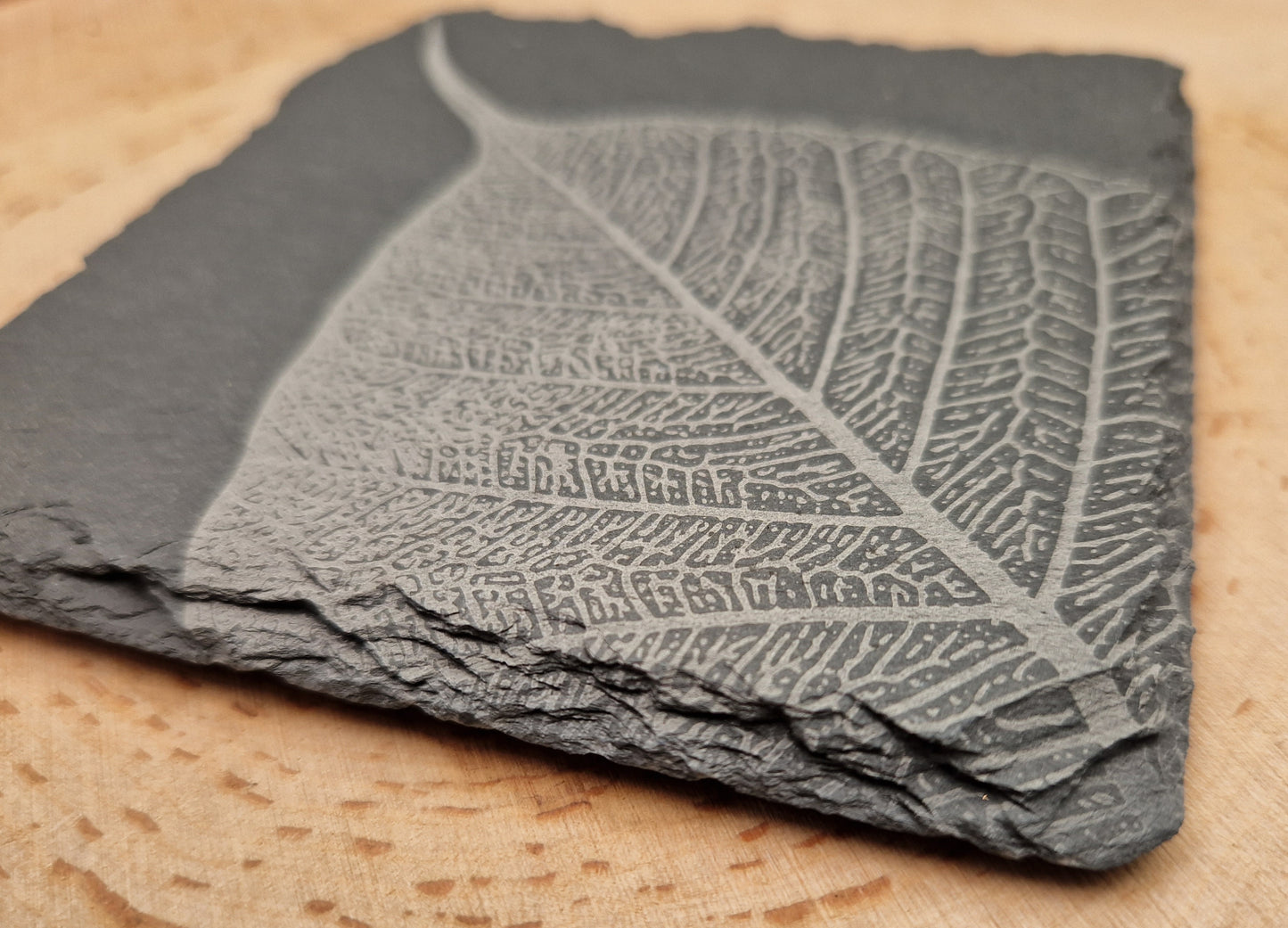 Close-up of a square slate coaster with intricate leaf vein design, highlighting natural edges and high-quality craftsmanship.