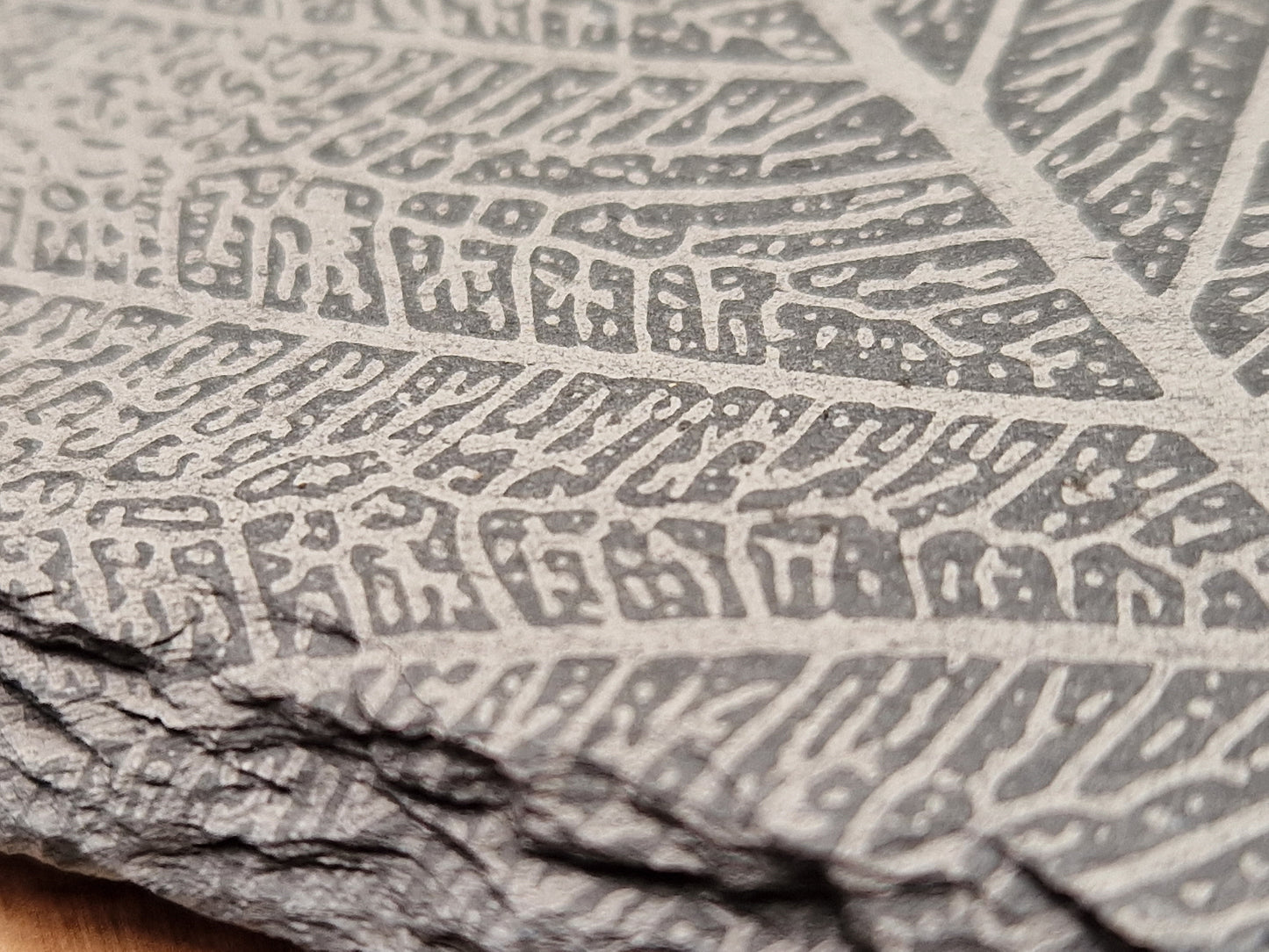 Close-up of a square slate coaster with intricate leaf vein design, highlighting natural edges and high-quality craftsmanship.