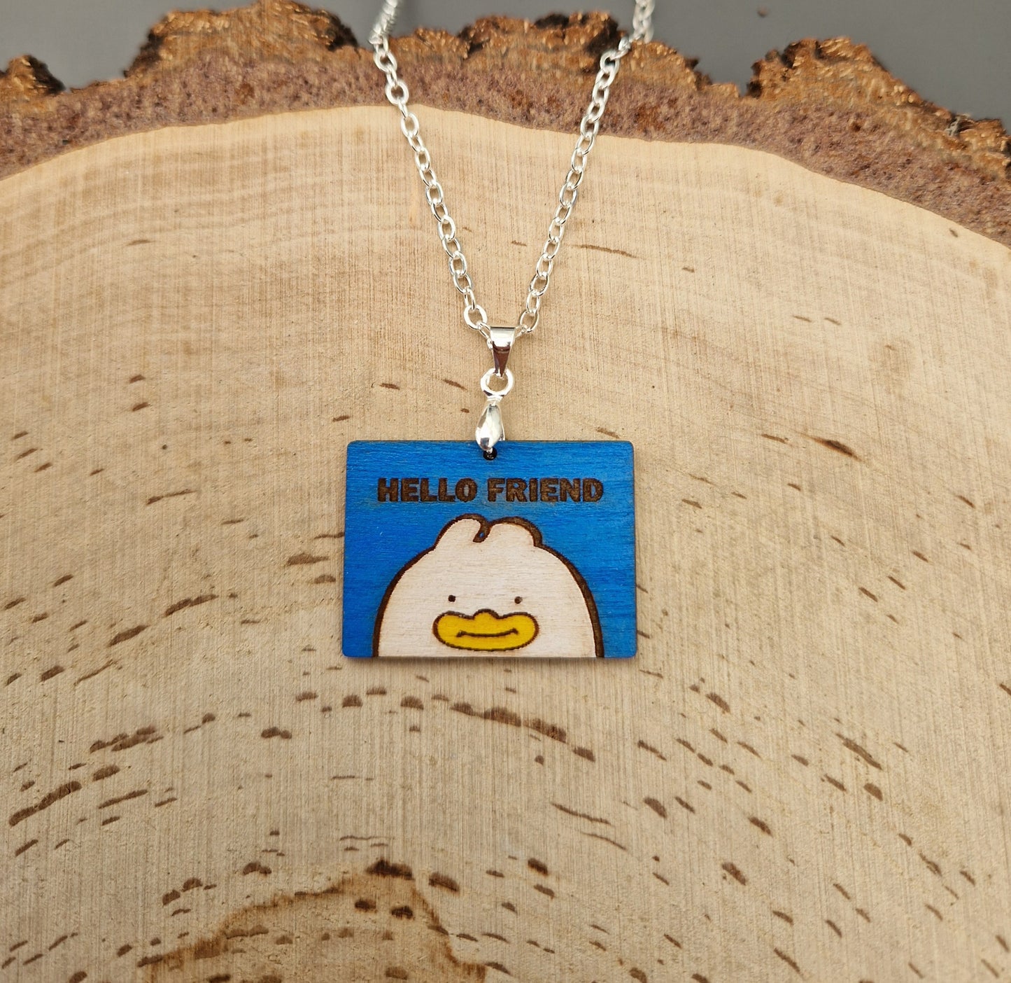 Necklace with a blue pendant featuring a kpop demon hunter Hello Friend character on a wooden surface