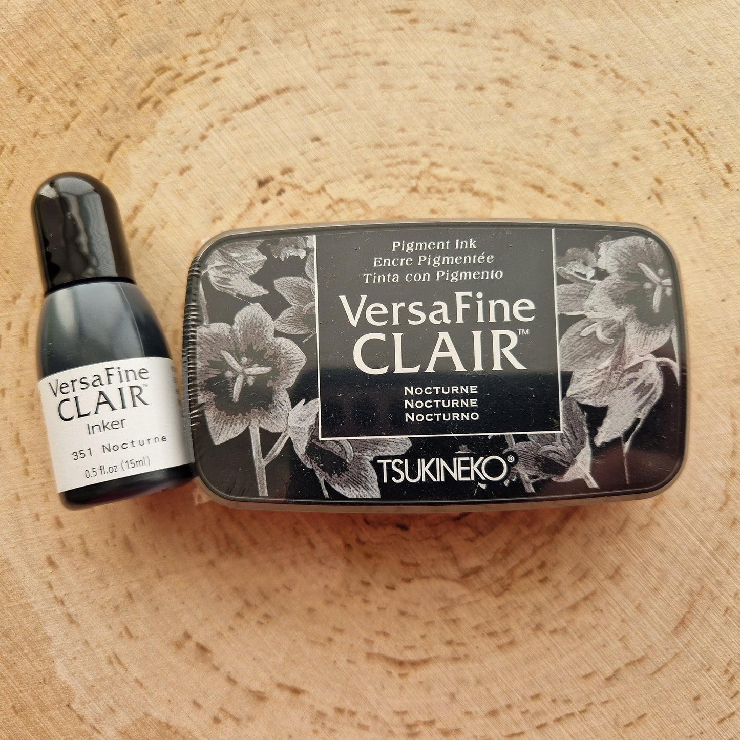 Versafine clair black ink pad and inker displayed on wooden background