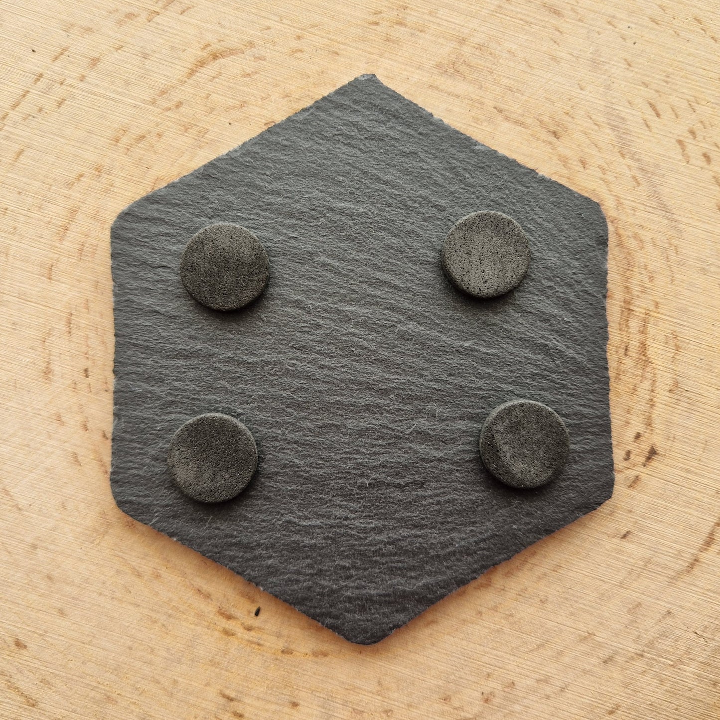 Back of a hexagonal slate coaster displayed on wooden background