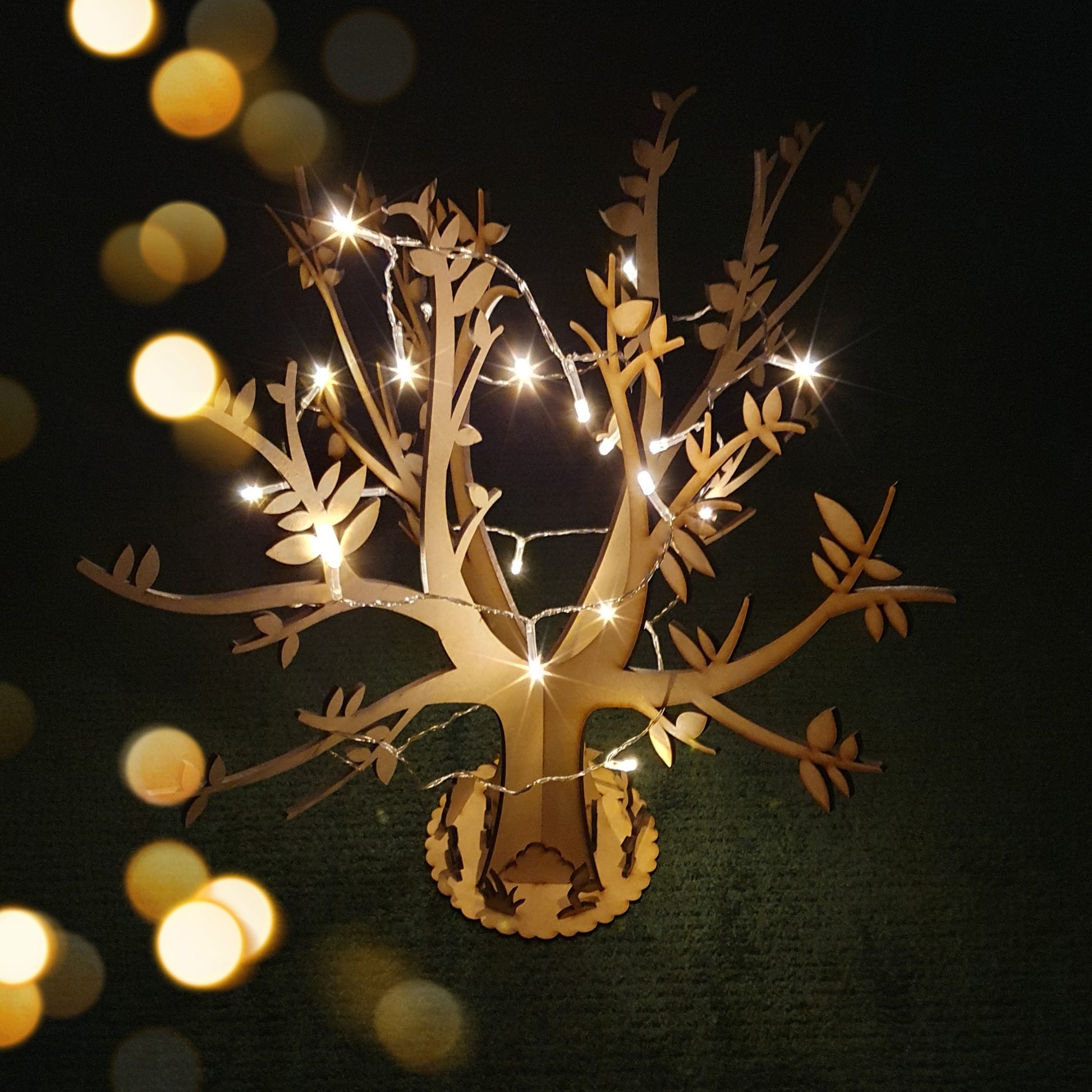 wooden tree with base displayed with black background and fairy lights